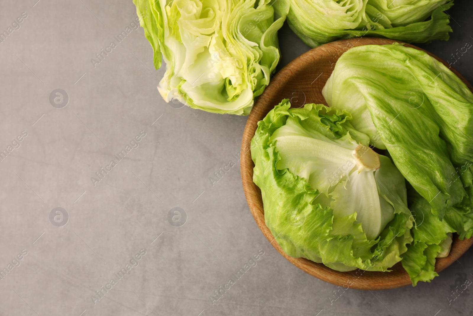 Photo of Fresh green cut and whole iceberg lettuce heads on grey table, flat lay. Space for text