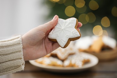 Woman with decorated Christmas cookie at table, closeup