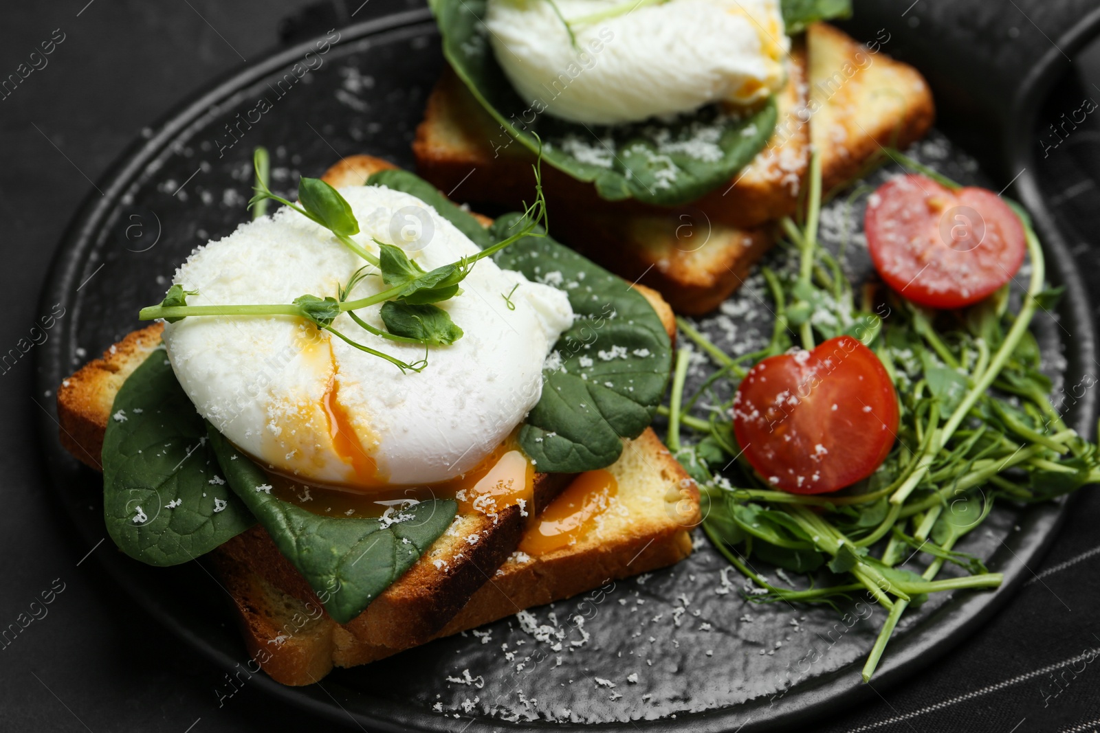 Photo of Delicious poached egg sandwiches served on slate board, closeup