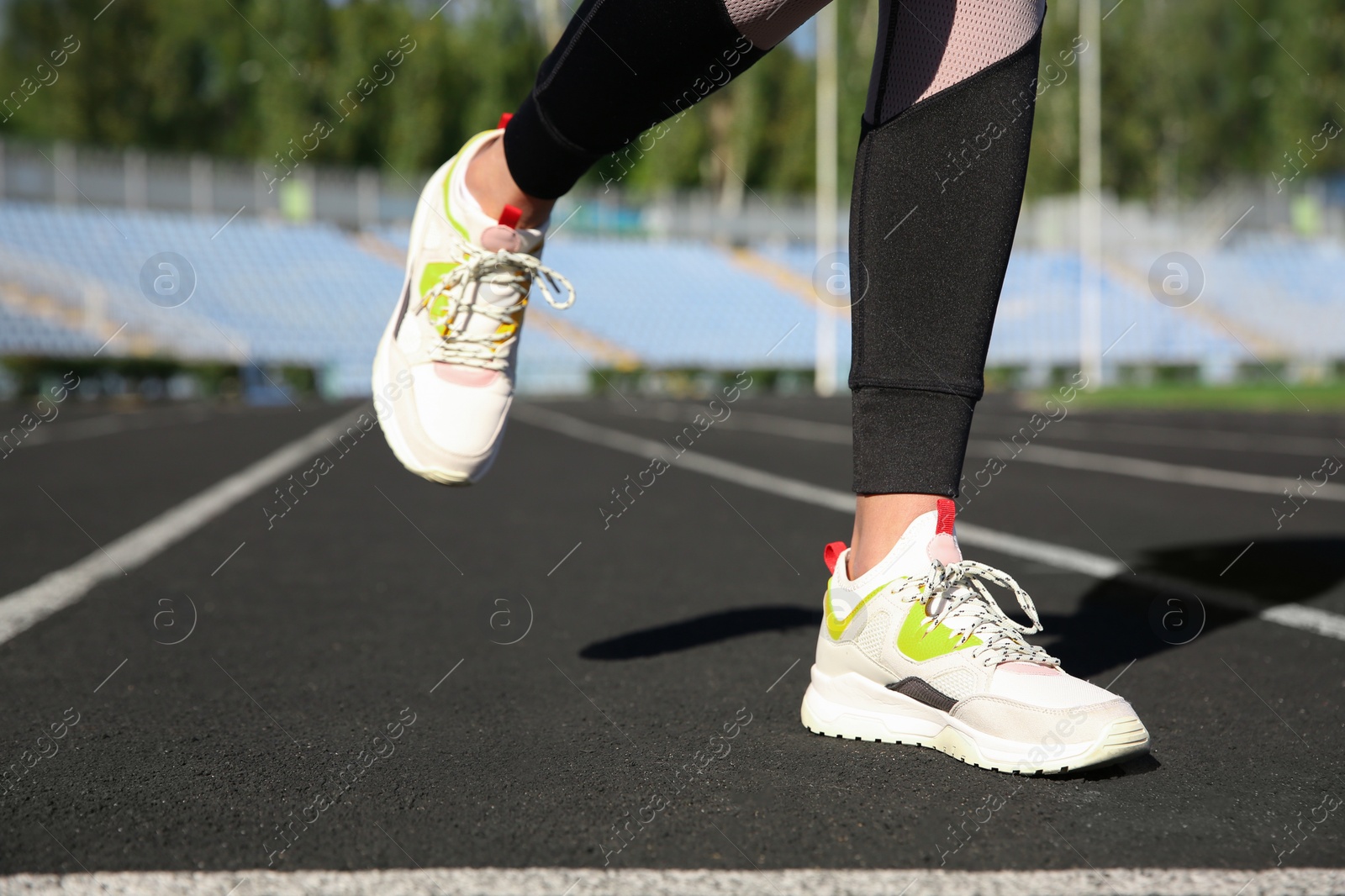 Photo of Sporty woman running at stadium on sunny morning, focus on legs