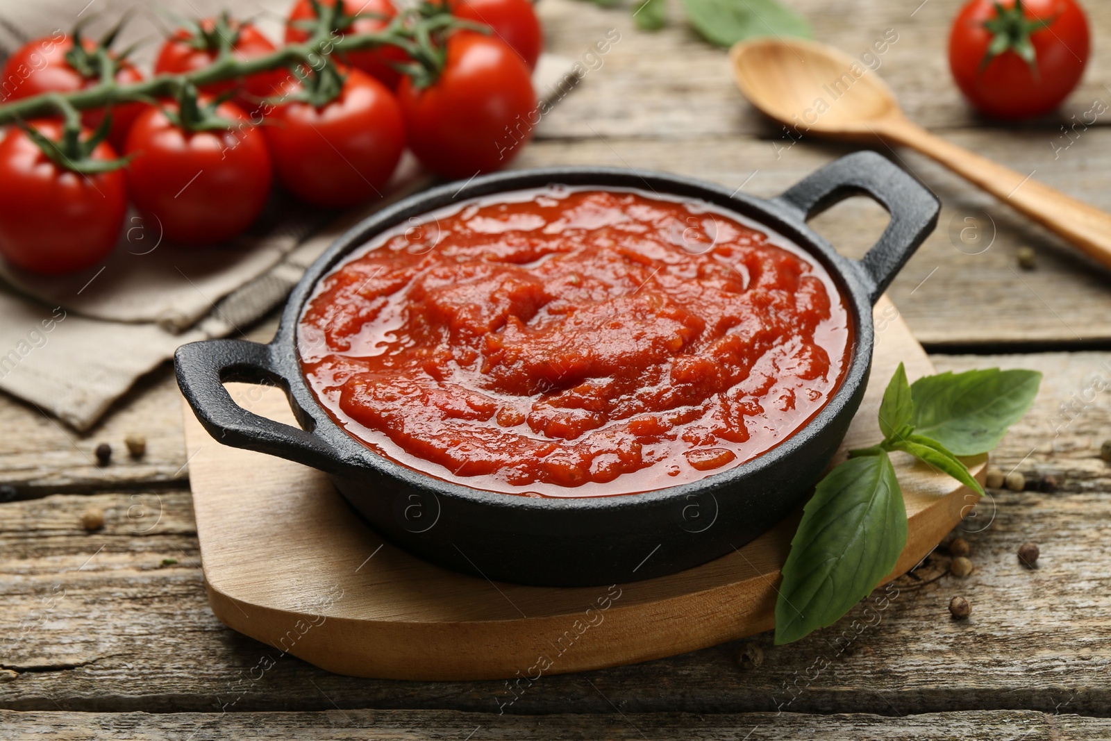 Photo of Homemade tomato sauce in bowl and basil on wooden table, closeup