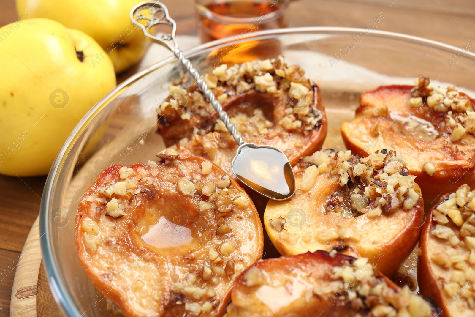 Photo of Tasty baked quinces with walnuts and honey in bowl on table, closeup