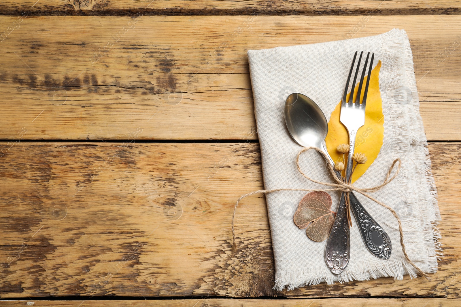 Photo of Seasonal table setting with autumn decorations, space for text. Cutlery and fallen leaves on wooden background, top view