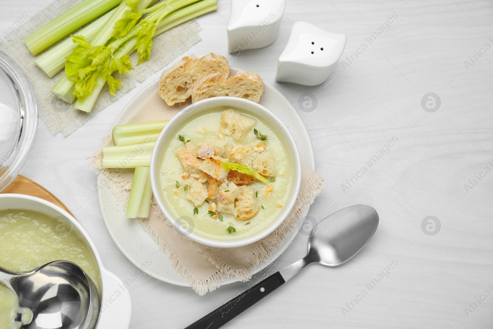 Photo of Delicious celery soup served on white wooden table, flat lay