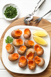 Photo of Delicious cooked snails served on white wooden table, flat lay