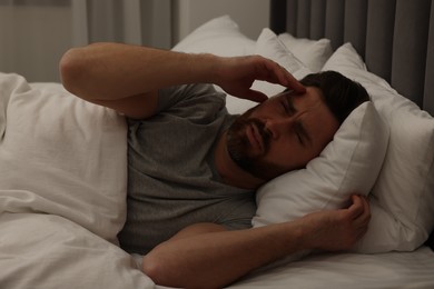 Photo of Man suffering from headache in bed at night