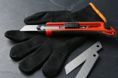 Glove, utility knife and blades on black table