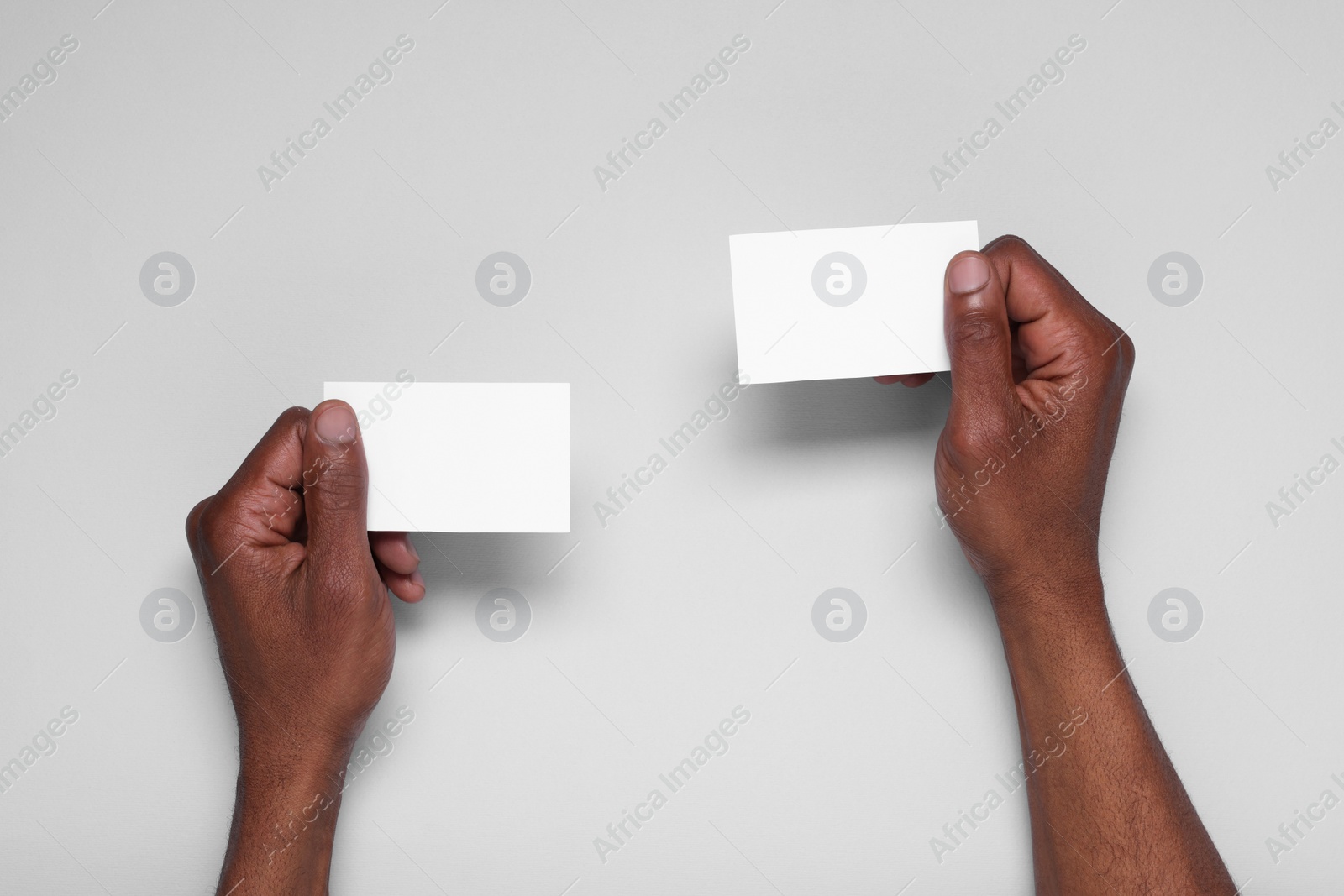 Photo of African American man holding paper cards on white background, closeup. Mockup for design