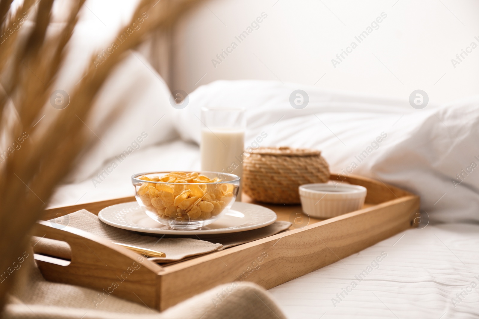 Photo of Corn flakes and milk in tray on bed.  Delicious morning meal