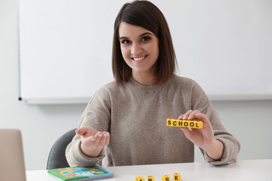 Photo of Happy female English teacher giving lesson indoors. Early childhood education