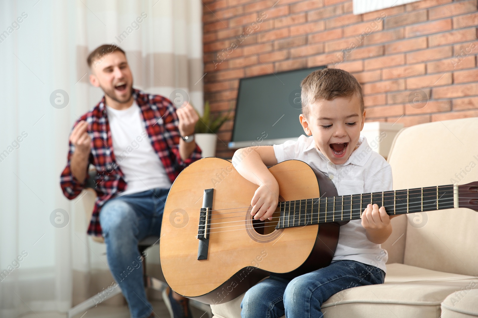 Photo of Father and son playing guitar and singing at home