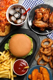 French fries, burger and other fast food on gray table, flat lay