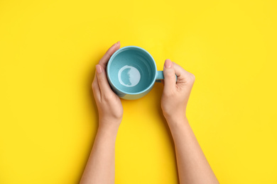 Photo of Woman with empty cup on yellow background, top view