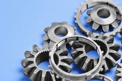 Photo of Different stainless steel gears on light blue background, closeup. Space for text