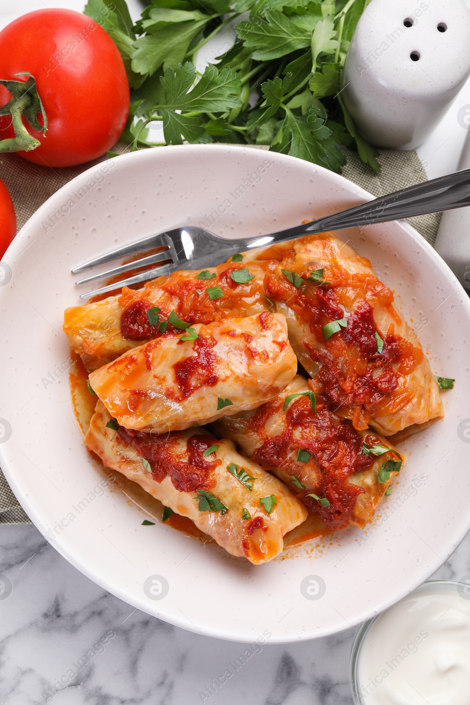 Photo of Delicious stuffed cabbage rolls cooked with homemade tomato sauce on white marble table, flat lay