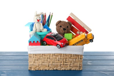 Photo of Wicker basket with different children's toys on blue wooden table against white background