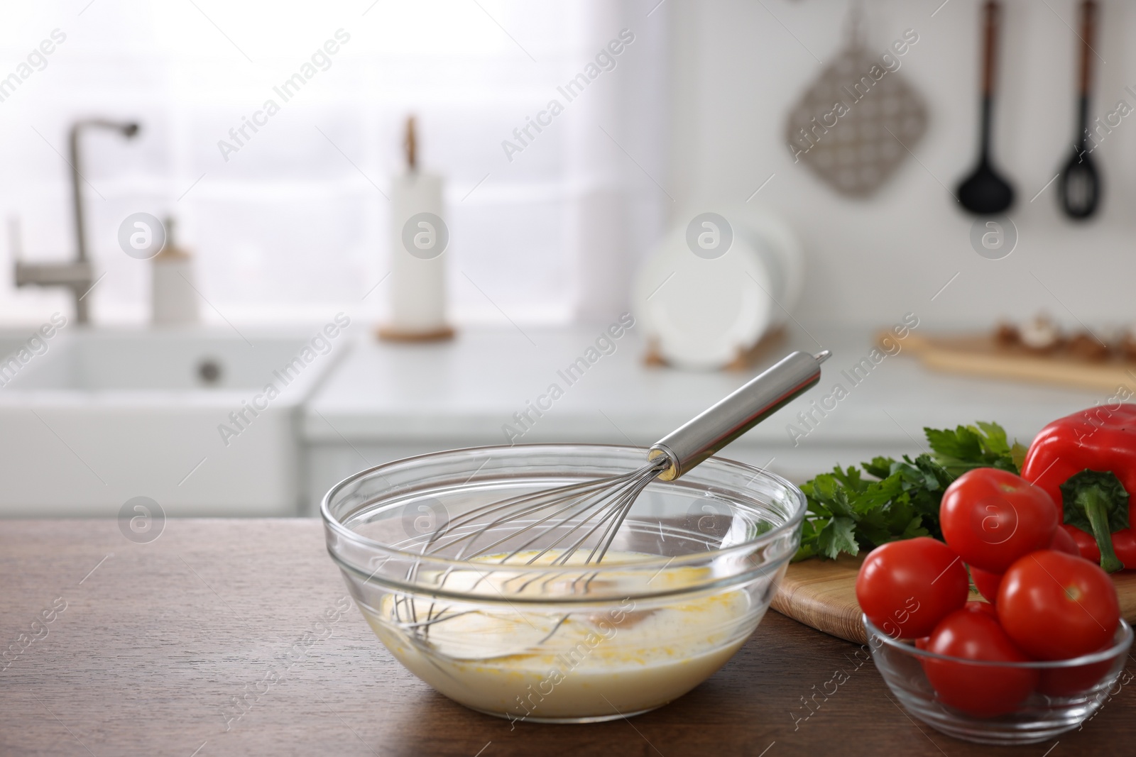 Photo of Whisk, bowl, beaten eggs and other ingredients on wooden table indoors, space for text