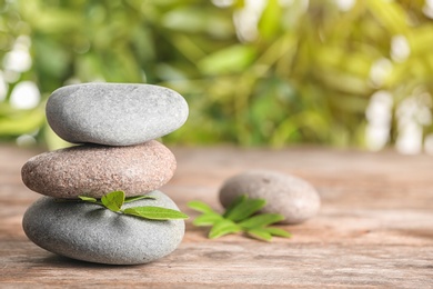 Spa stones and bamboo leaves on table against blurred background. Space for text