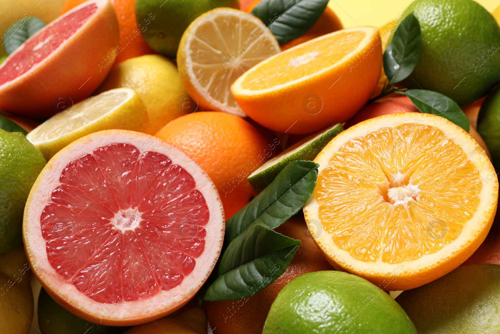 Photo of Different fresh citrus fruits and leaves as background, closeup