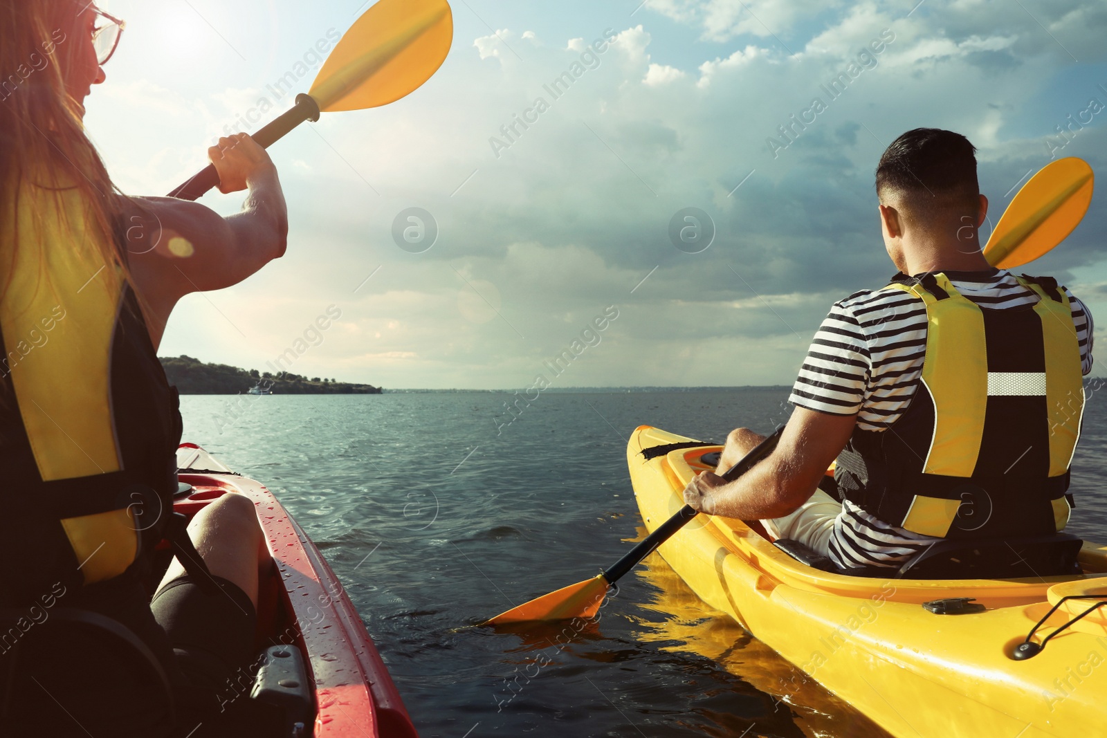 Photo of Couple in life jackets kayaking on river, back view. Summer activity