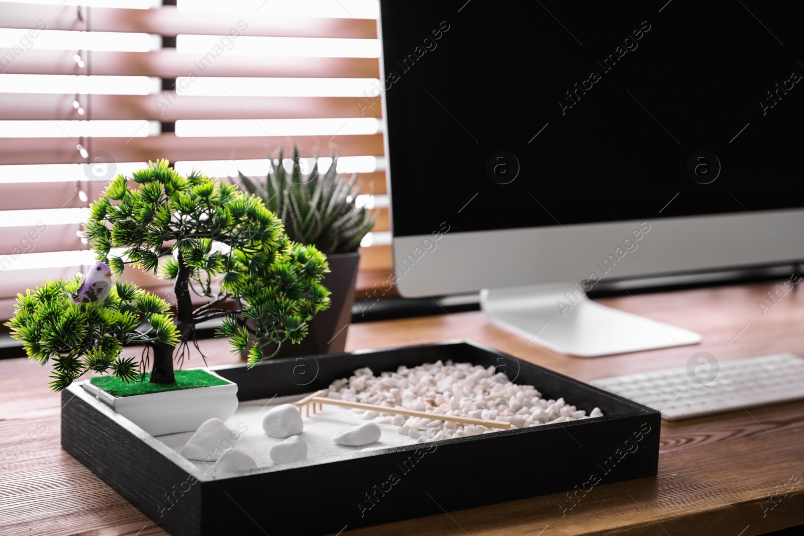 Photo of Modern workplace with beautiful miniature zen garden and computer in room