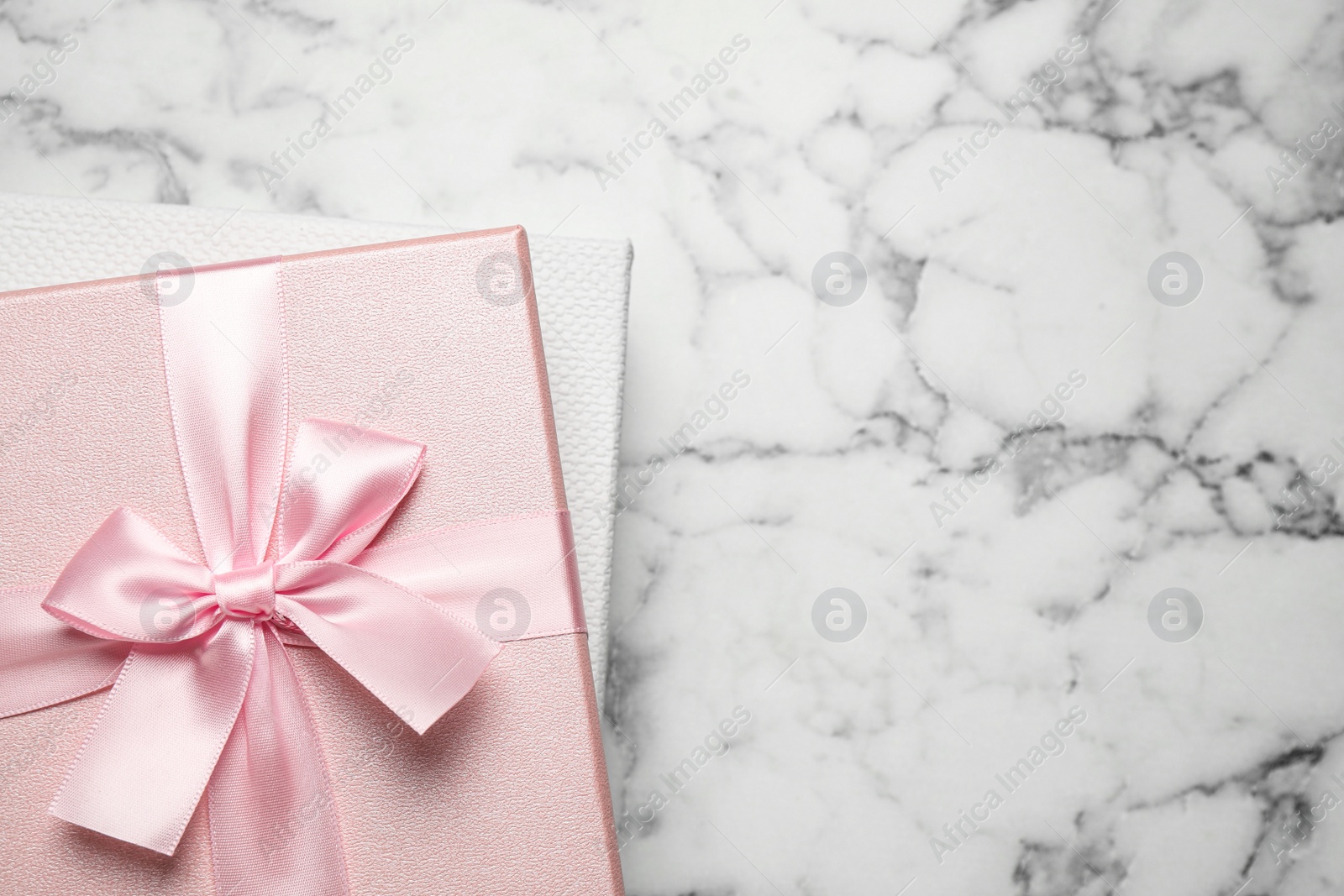 Photo of Elegant gift boxes on white marble table, top view. Space for text