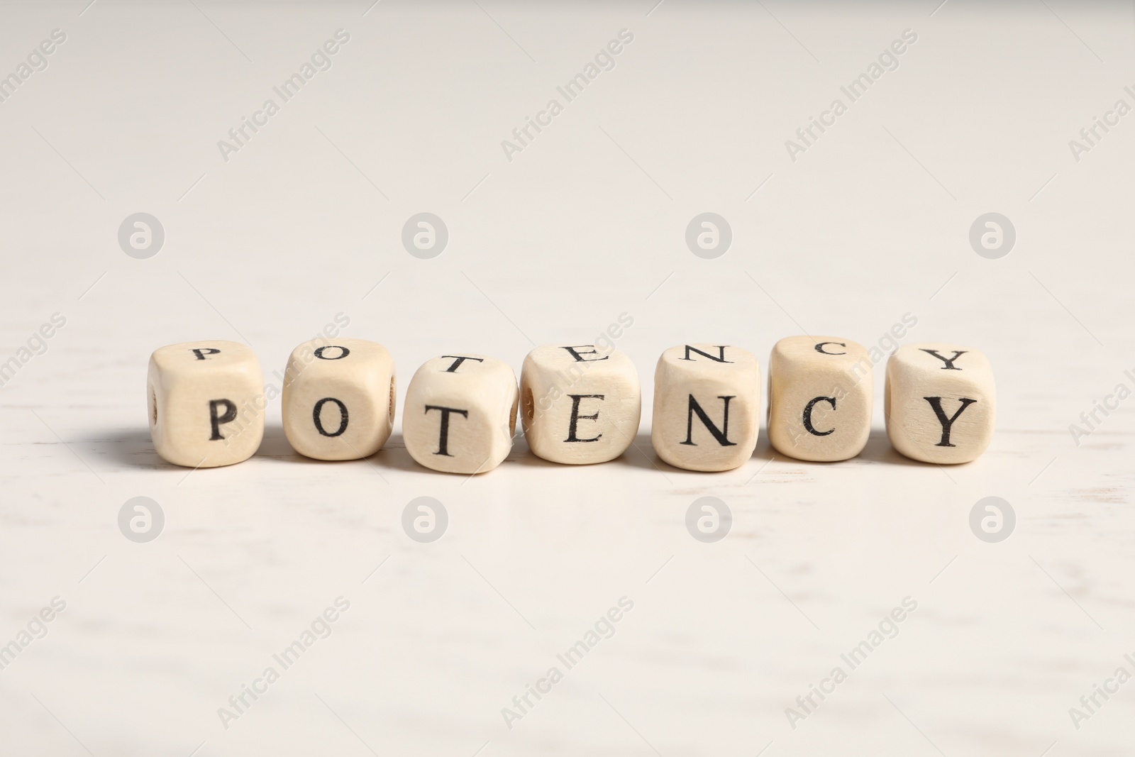 Photo of Wooden cubes with word Potency on white table, closeup