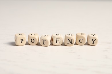 Photo of Wooden cubes with word Potency on white table, closeup