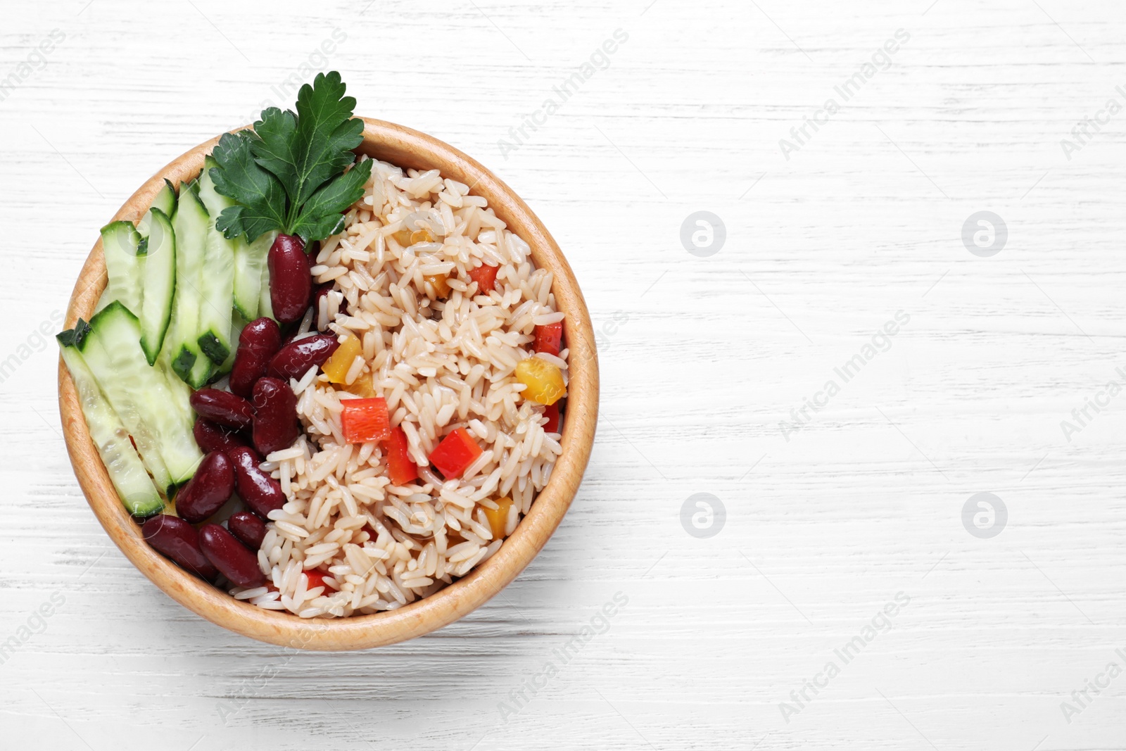 Photo of Delicious rice with beans on white wooden table, top view. Space for text