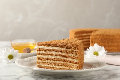 Slice of delicious layered honey cake served on white marble table. Space for text