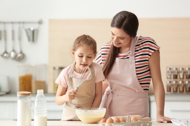 Mother and her daughter making dough at table in kitchen