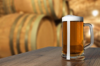 Image of Mug with fresh beer on wooden table in cellar, space for text