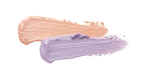 Photo of Strokes of pink and purple color correcting concealers isolated on white, top view