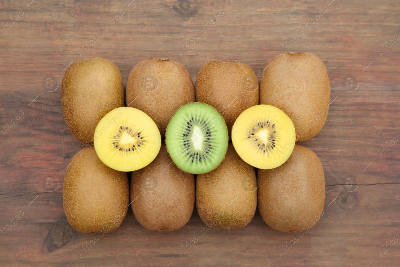 Photo of Many whole and cut fresh kiwis on wooden table, flat lay