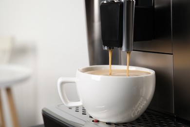 Espresso machine pouring coffee into cup against blurred background, closeup. Space for text