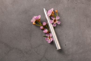 Photo of Metal bullet and beautiful flowers on grey textured table, above view