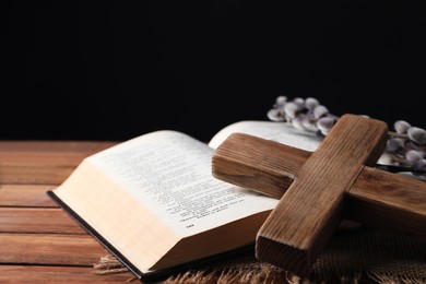 Photo of Cross, Bible and willow branches on wooden table