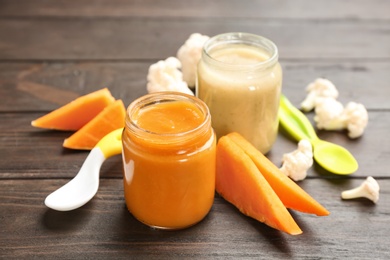 Jars with healthy baby food and ingredients on table