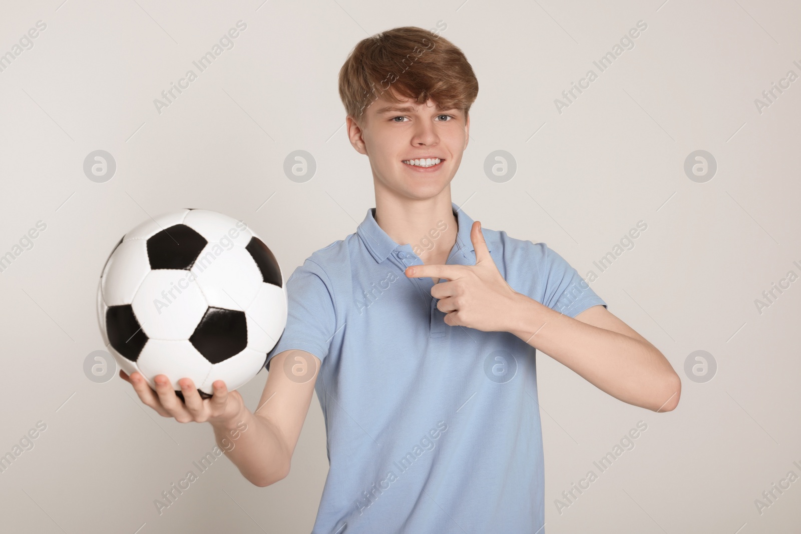 Photo of Teenage boy with soccer ball on light grey background