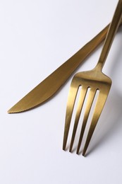 Photo of Stylish golden cutlery. Fork and knife on white background, closeup