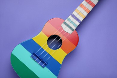 Colorful ukulele on purple background, top view. String musical instrument