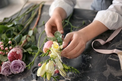 Photo of Female florist creating beautiful bouquet at table