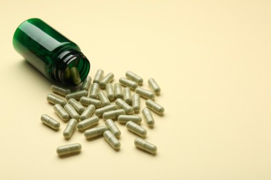 Photo of Vitamin pills and bottle on beige background. Space for text