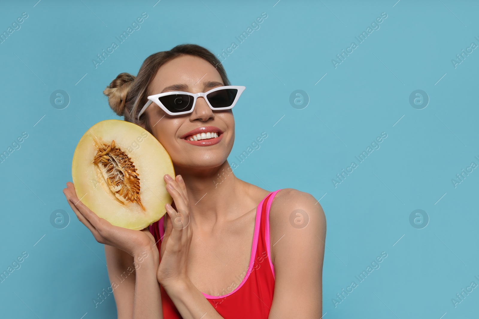 Photo of Young woman with fresh melon on light blue background, space for text. Exotic fruit