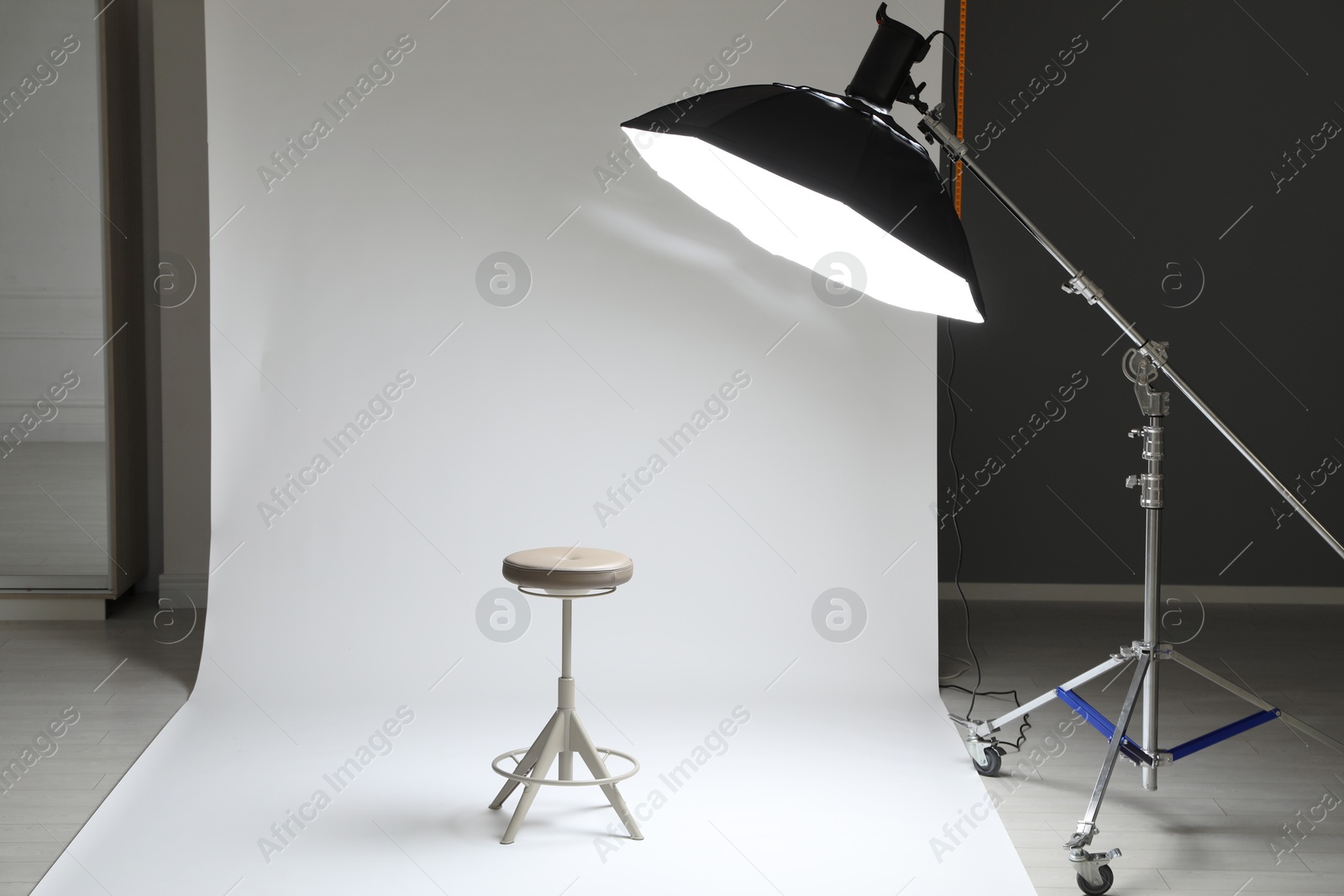 Photo of White photo background, stool and professional lighting equipment in modern studio