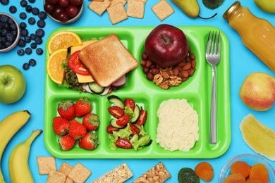 Photo of Flat lay composition with tray and tasty food on light blue background. School lunch