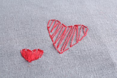 Photo of Embroidered red hearts on gray cloth, closeup