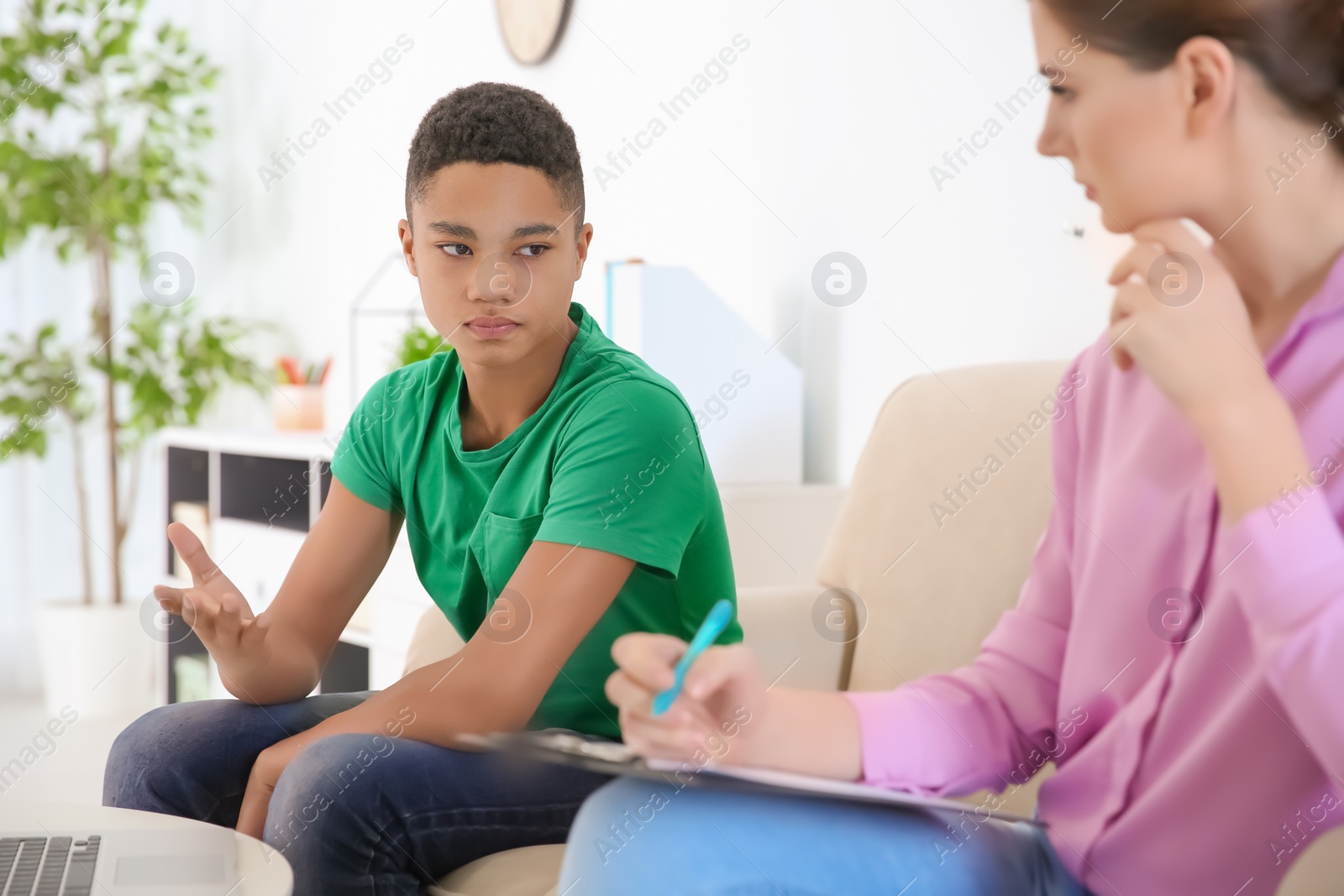 Photo of Female psychologist working with African American teenage boy in office