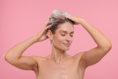 Photo of Beautiful woman washing hair on pink background
