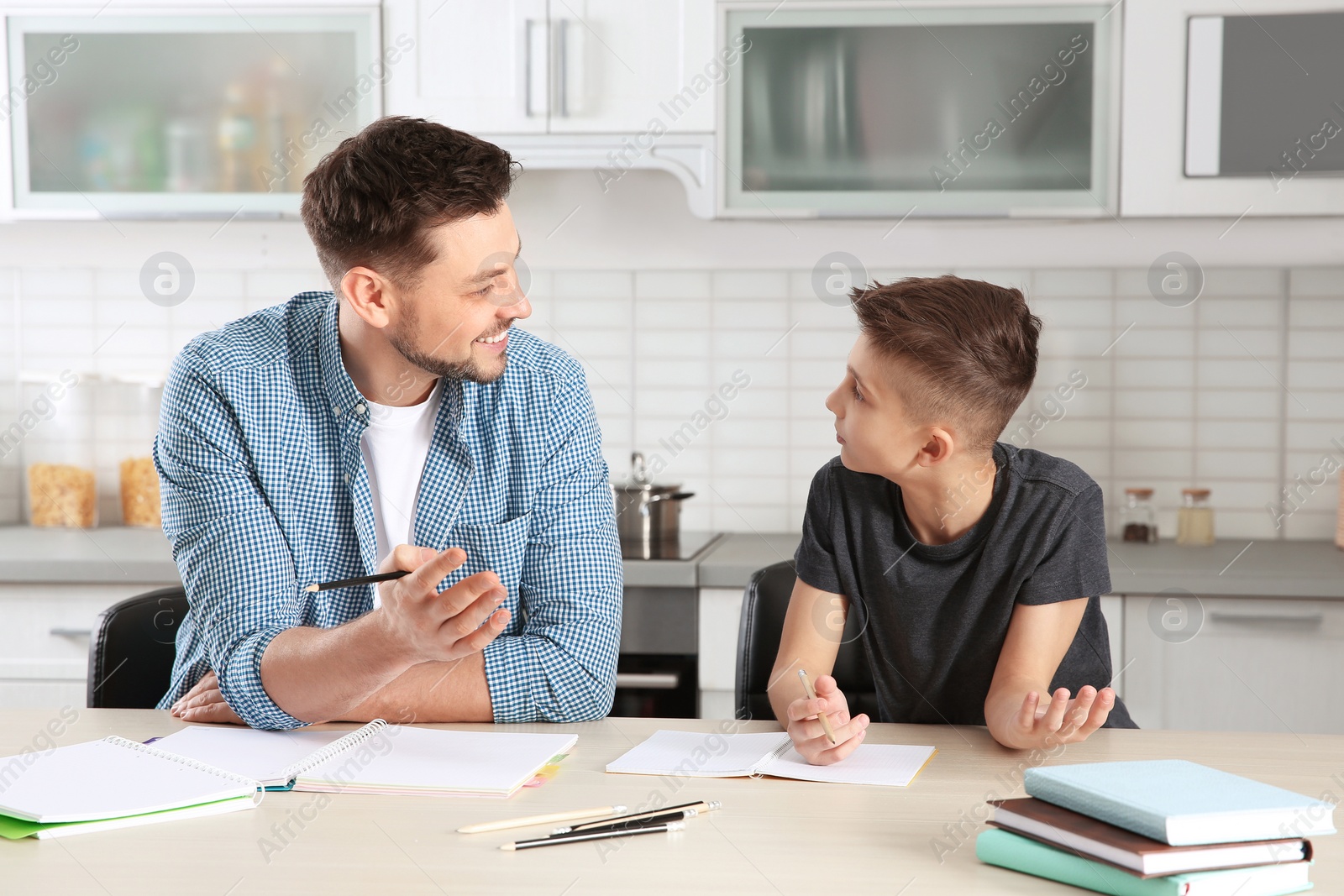 Photo of Dad helping his son with homework in kitchen